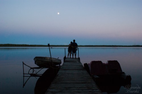 A couple standing out on a dock in the evening
