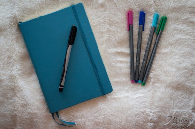 A blue bullet journal with assorted markers