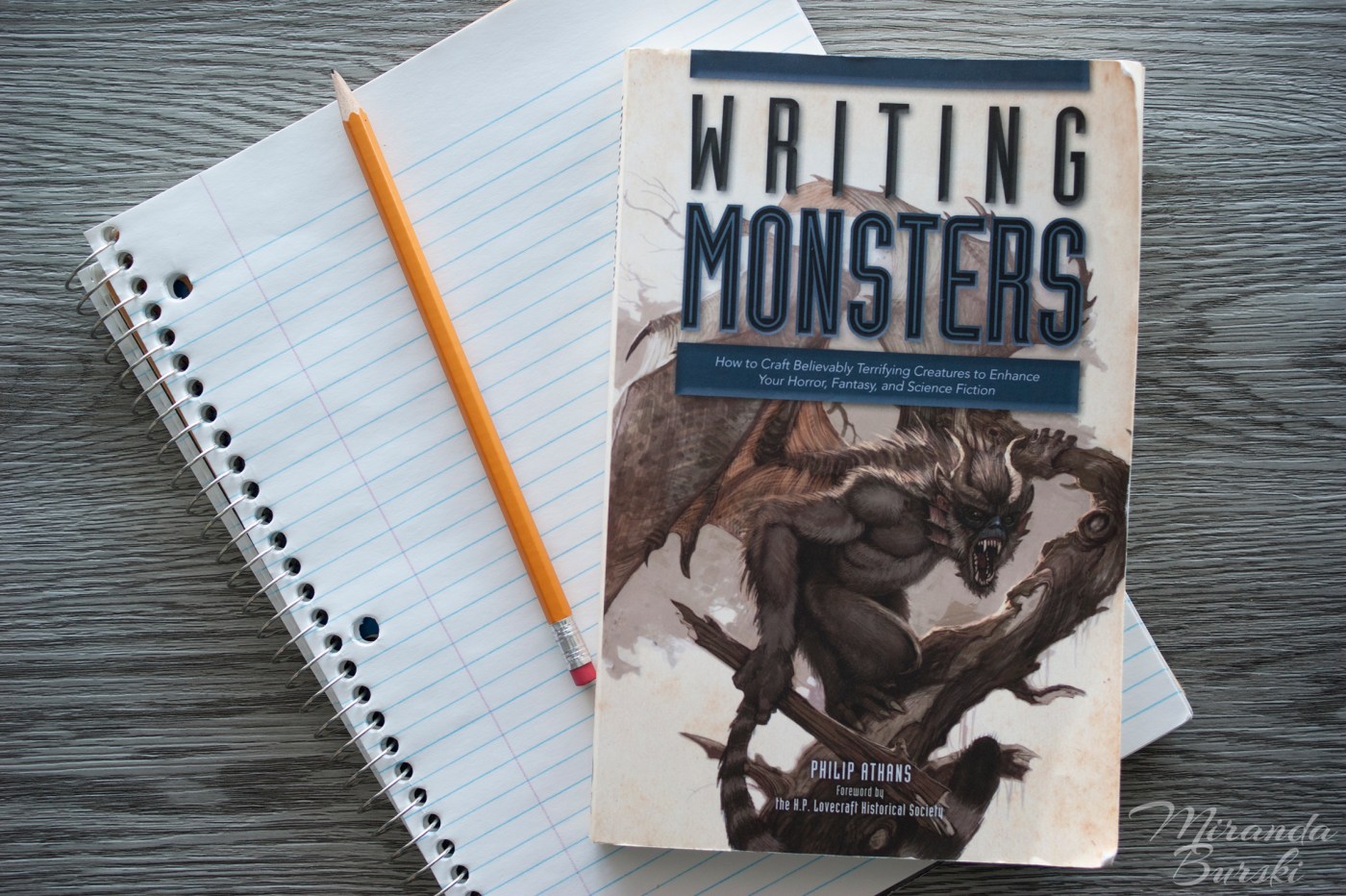A copy of Writing Monsters, by Philip Athans, on top of a notebook and pencil