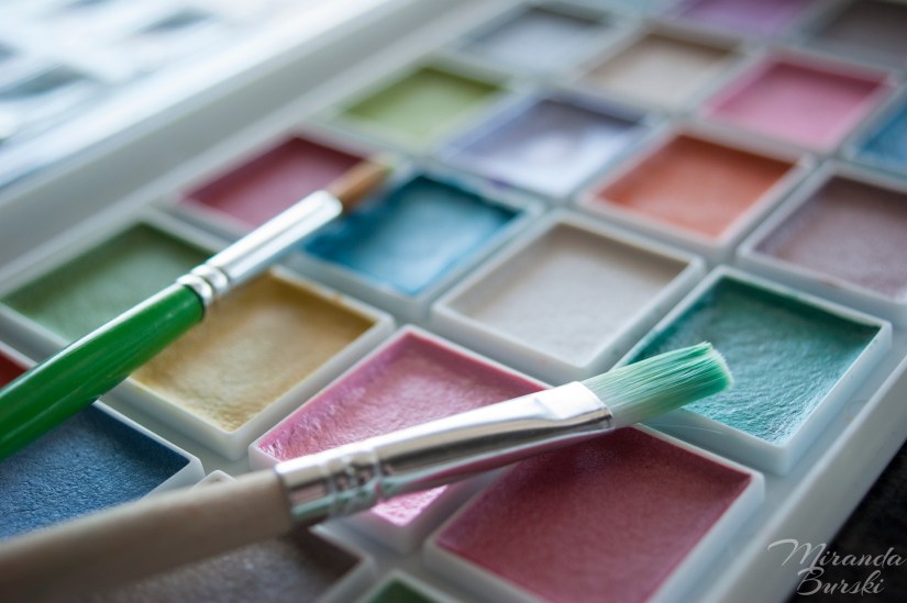 A palette of watercolour paints and two paintbrushes