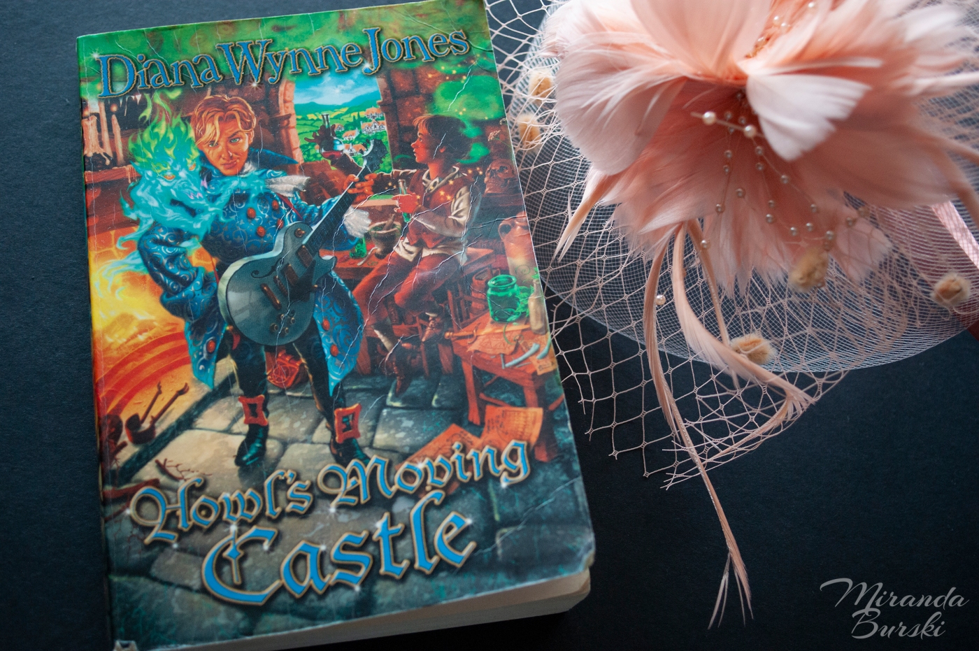 A copy of Howl's Moving Castle, by Diana Wynne Jones, alongside a pink hat.