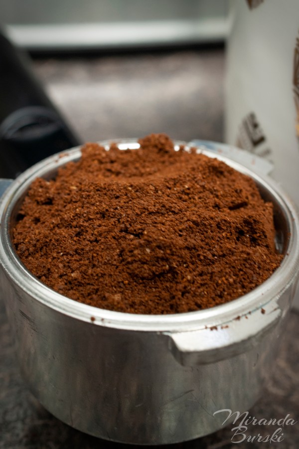 An espresso cup filled with ground coffee beans.