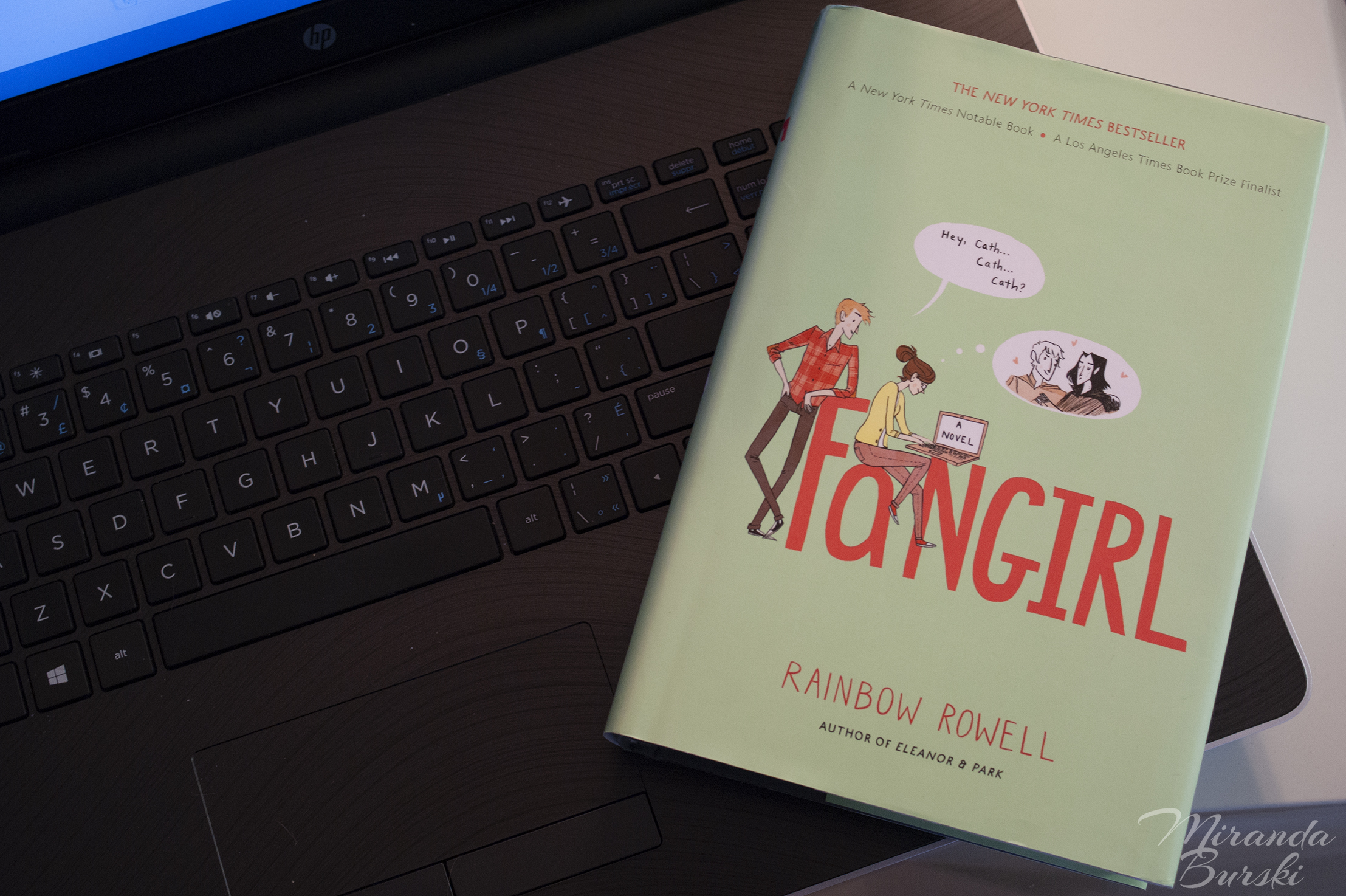 A copy of Fangirl, by Rainbow Rowell, sitting on a laptop keyboard.