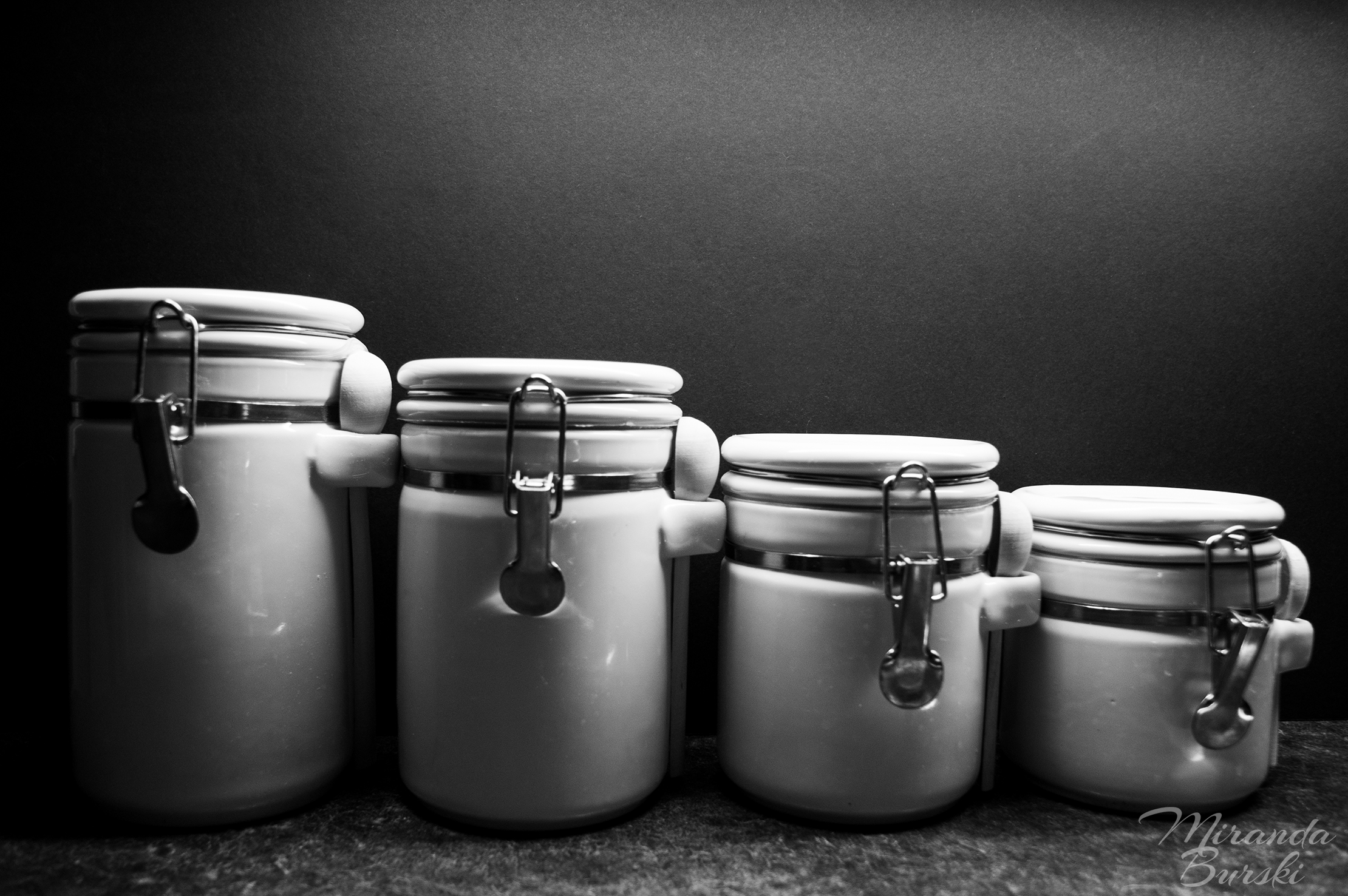 A black and white photo of four white canisters.