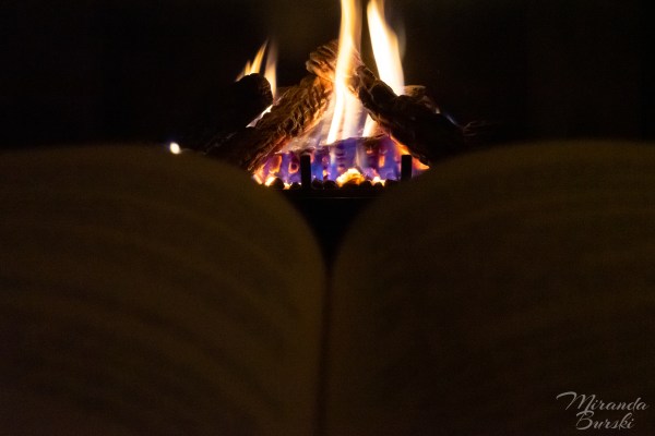 A book open in front of a lit fire.
