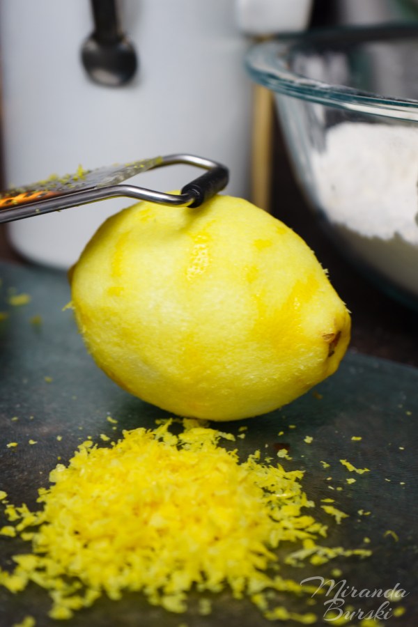 A lemon beside zest and a zester.