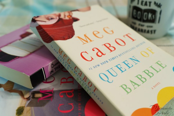 The Queen of Babble book series, by Meg Cabot, beside a coffee mug.