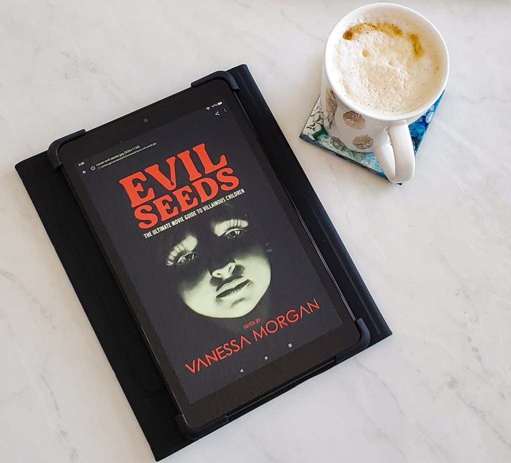 An e-book copy of Evil Seeds, sitting beside a latte.